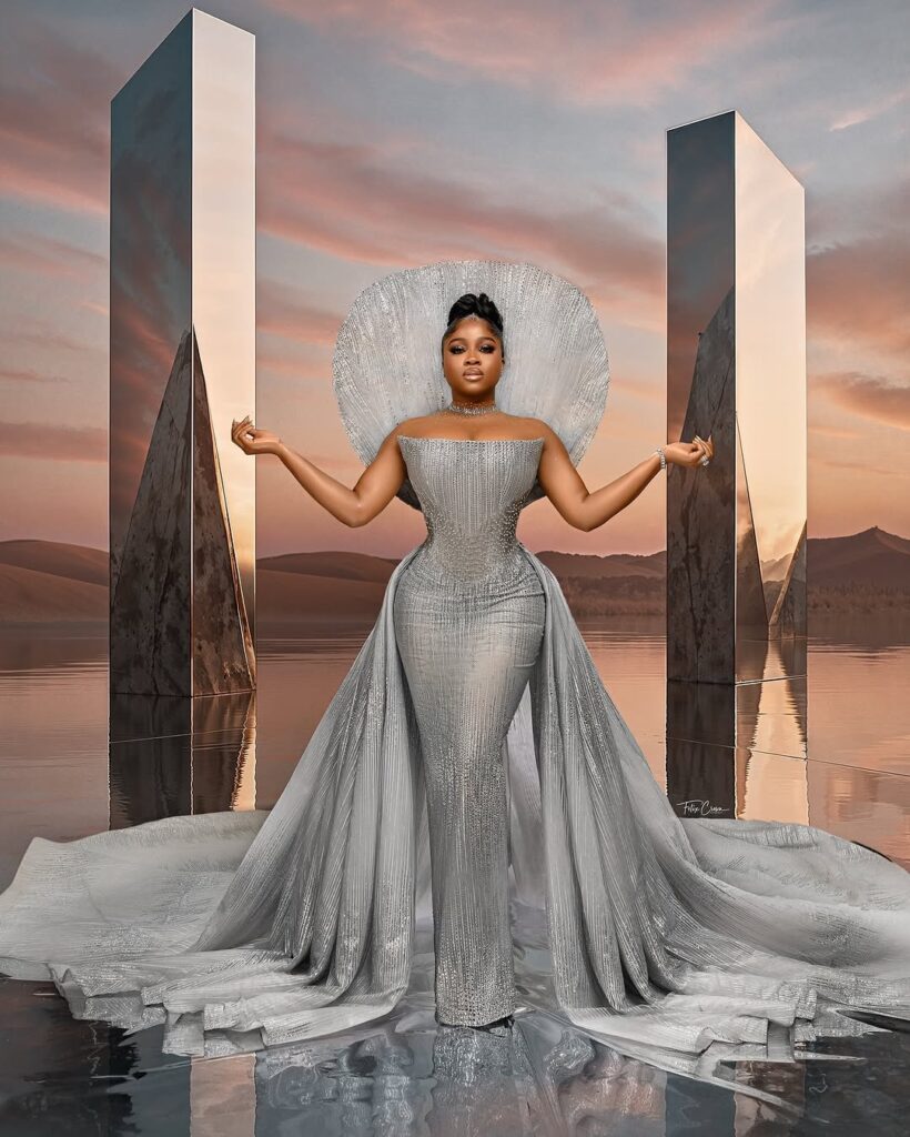 Silver dress with a standing cape and long train by Veekee James Official.
